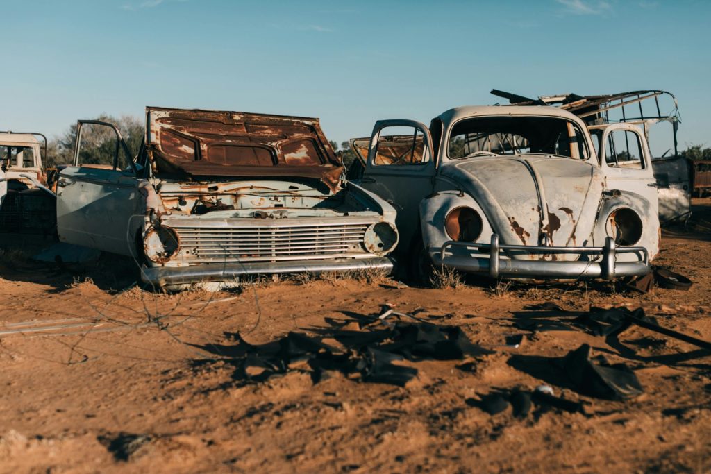 Old cars with a bonnet open showing rust and decay